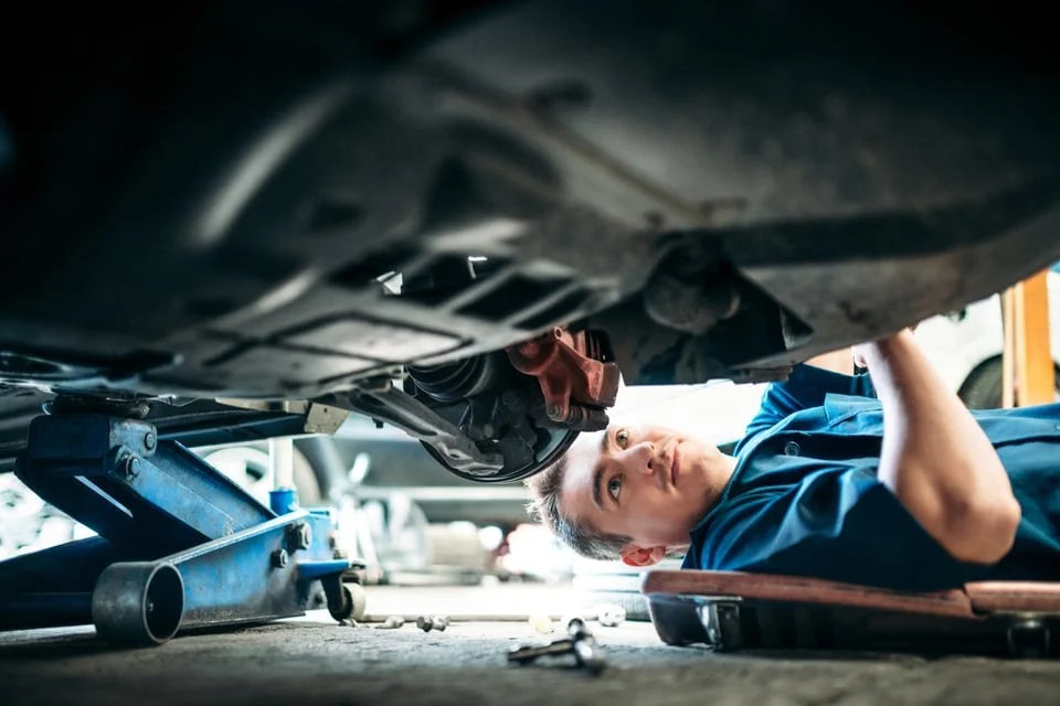 Technician inspecting a vehicle underbody on a lift